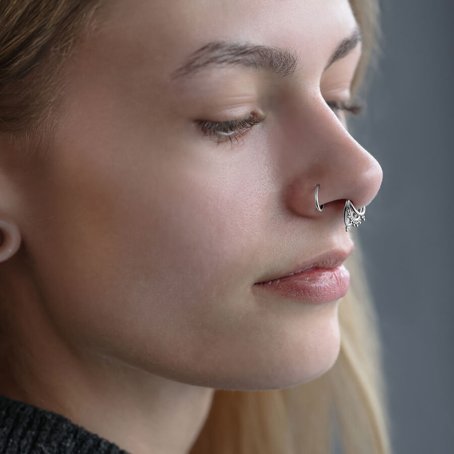 Primer plano de un Triple Oriental Clicker de plata en el septum de una persona