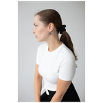 Mujer con camiseta blanca lleva Little Soulmate Hoops plateados frente a un fondo gris