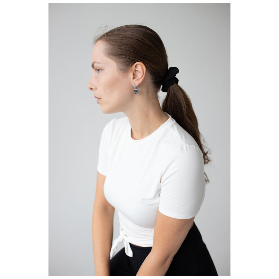 Mujer con camiseta blanca lleva Little Soulmate Hoops plateados frente a un fondo gris