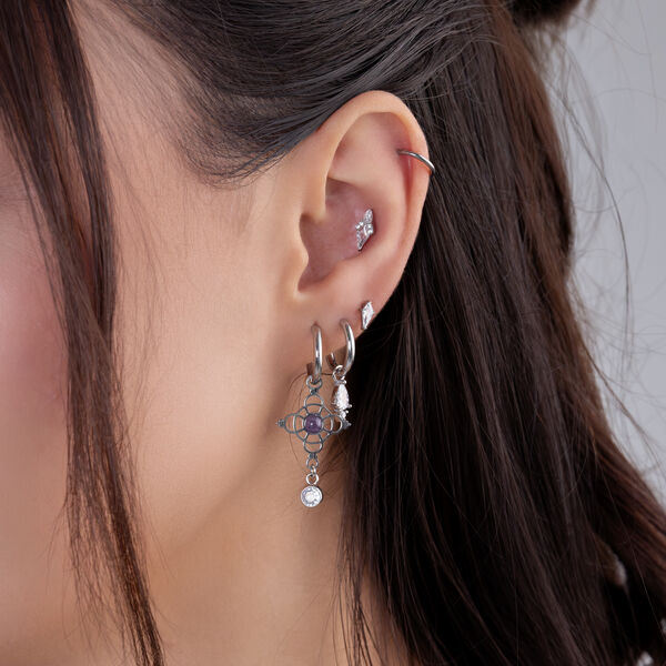 Silberne Amethyst-Ohrringe in verschiedenen Ohrlöchern einer Person mit dunklem Haar