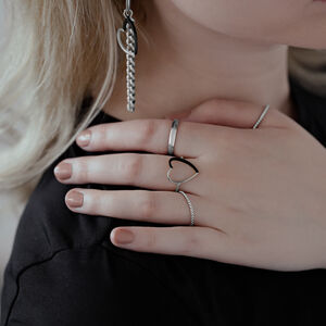 Zweifarbiger Herzring aus Chirurgenstahl Nahaufnahme einer Hand mit zweifarbigem Herzring aus Chirurgenstahl, getragen neben anderen Ringen