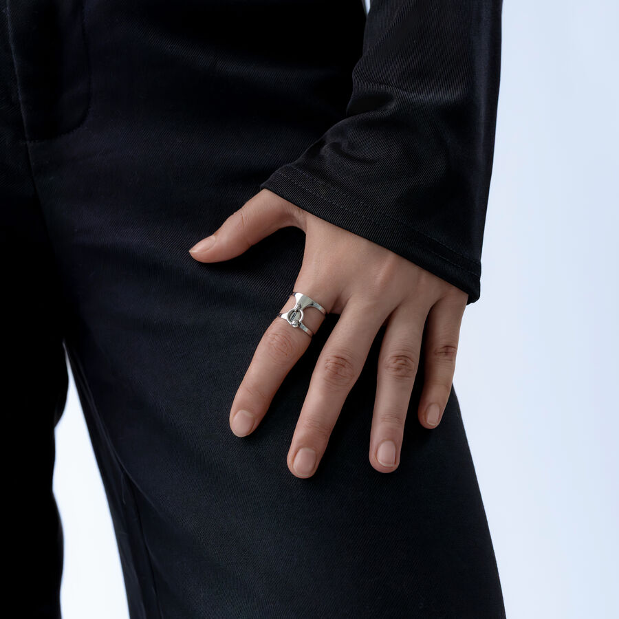 Anello argento su una mano, persona con abbigliamento nero su sfondo chiaro