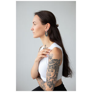 Magnolia Hoops Ohrringe im eleganten Design Frau mit Magnolia Hoops Ohrringen, Edelstahl in Schwarz auf grauem Hintergrund