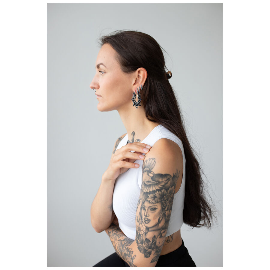 Donna con orecchini Magnolia Hoops, acciaio inossidabile nero su sfondo grigio