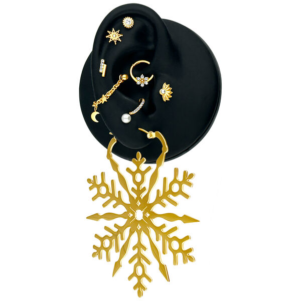 Cadena de piercing dorada con motivos de luna y estrellas en un expositor negro para orejas