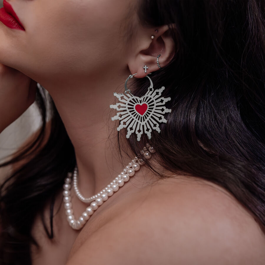 Mujer con pendientes Sacred Heart en plata y negro, primer plano