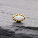 Ovaler synthetischer Opal in goldener Fassung auf grauem Hintergrund