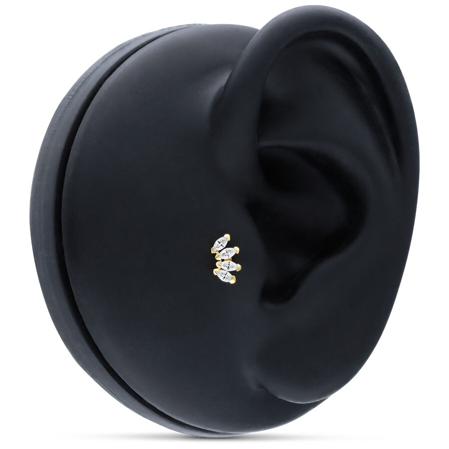 Accesorio de oro con cuatro cristales claros sobre modelo de oreja negro