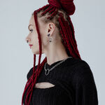 Mujer con trenza roja lleva pendiente de calavera plateado sobre fondo claro