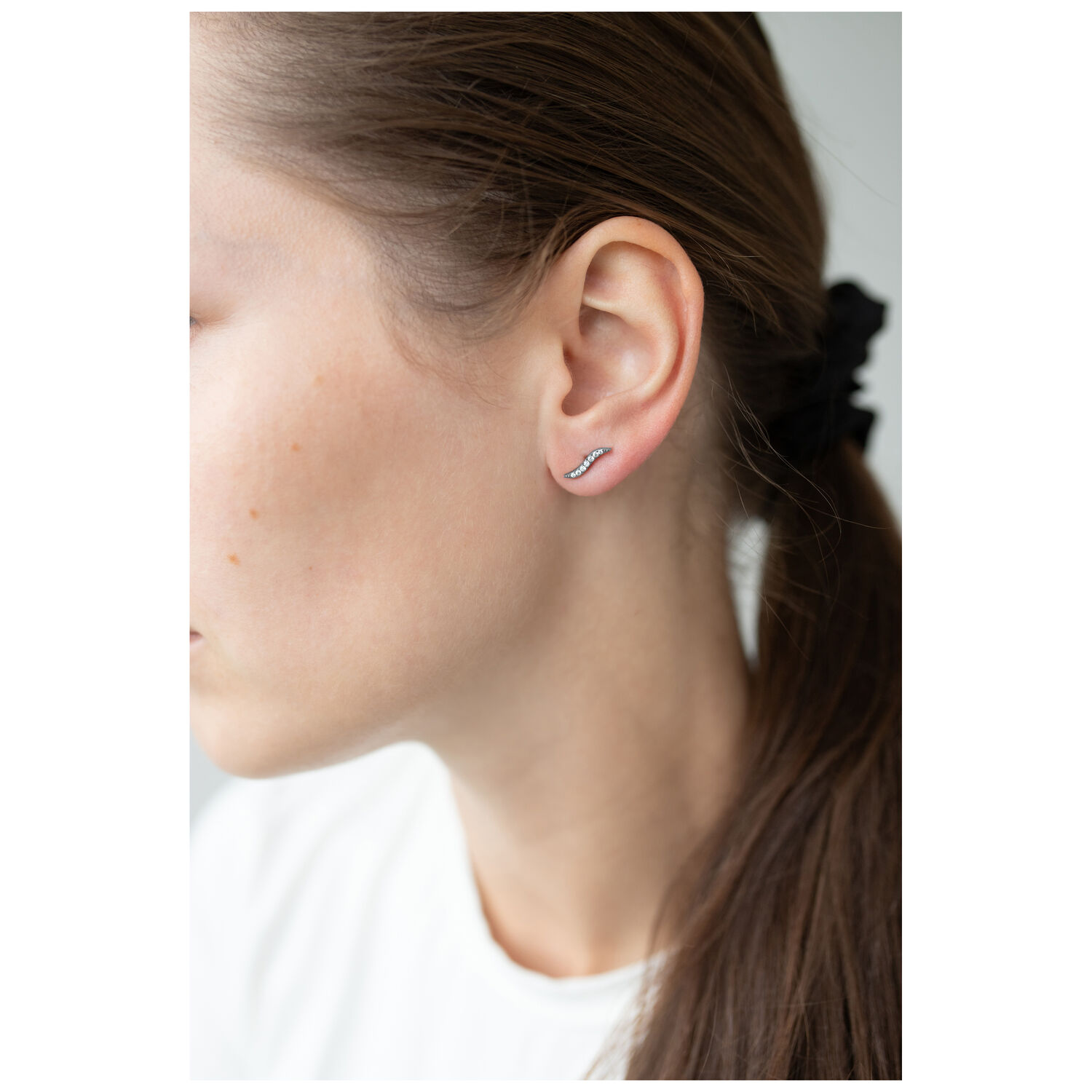 Elegante Kristall-Ohrstecker am Ohr getragen Frau mit braunem Haar trägt eleganten Kristall-Ohrstecker in Silber