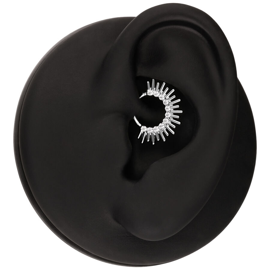 Clicker per septum argento a forma di raggi di sole in un orecchio nero su sfondo bianco