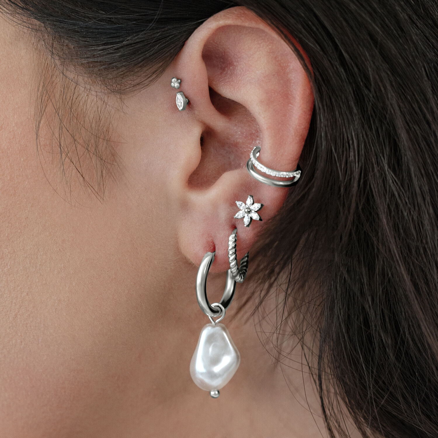 Barocke Perlen-Ohrringe in Silber Silberne Barock-Perlenohrringe an einem Ohr mit mehreren Piercings.