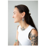 Donna sorridente con orecchini Oracle Hoops in argento su sfondo grigio