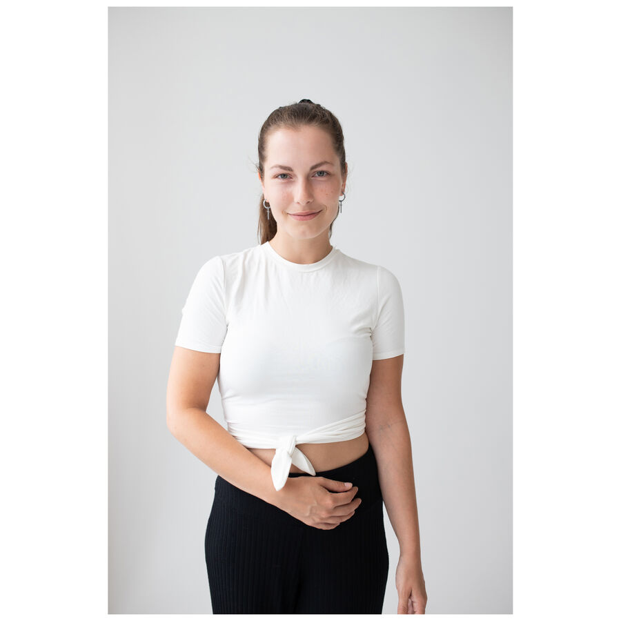 Mujer con blusa blanca y pantalones negros lleva aros Little Cross en plata sobre fondo blanco
