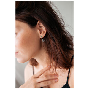 Silberne Little Shell Hoops im Ohr getragen Silberne Ohrringe in Muschelform an einem Ohr mit braunen Haaren und heller Haut