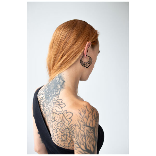 Mujer con cabello rojo lleva pendientes de pentagrama negro sobre fondo blanco