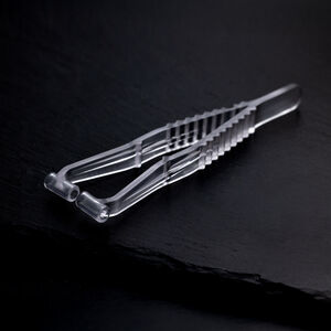 Sterile Septum Piercingzange auf schwarzem Hintergrund Transparente Septum Piercingzange aus Kunststoff auf dunklem, glattem Hintergrund