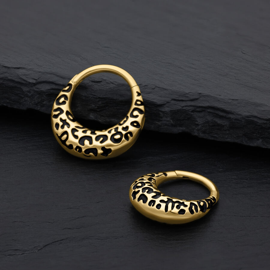 Dos clickers para septum dorados con estampado de leopardo sobre fondo negro