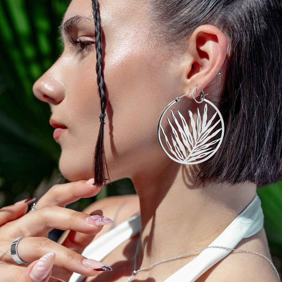 Orecchini Noble Leaf Hoops in argento su donna con capelli intrecciati e sfondo tropicale