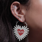 Pendientes plateados en forma de corazón con diseño de alambre de púas en una oreja