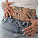 Bananabell a tre fili con cristalli su un ventre tatuato con jeans.