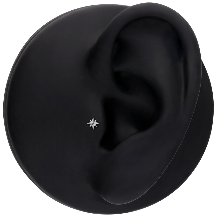 Accessorio argento a forma di stella in un modello di orecchio nero, ambiente studio