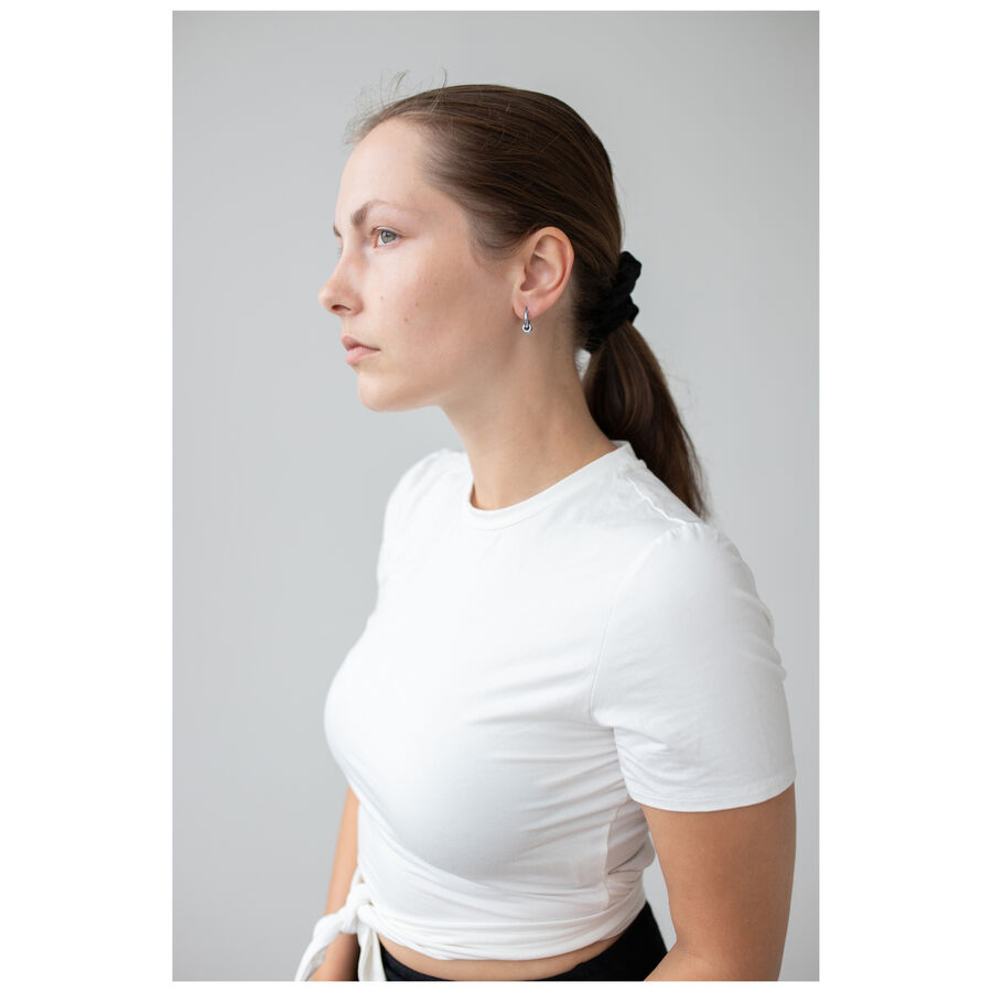 Donna con orecchini Little 5 Rings Hoops in nero e argento su sfondo grigio