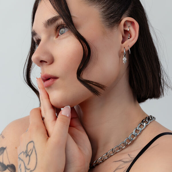 Mujer con Mini Lollipop aros, pelo corto, tatuajes, fondo blanco