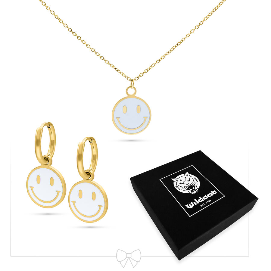 Collar dorado con colgante de Smiley y pendientes a juego junto a caja negra de Wildcat