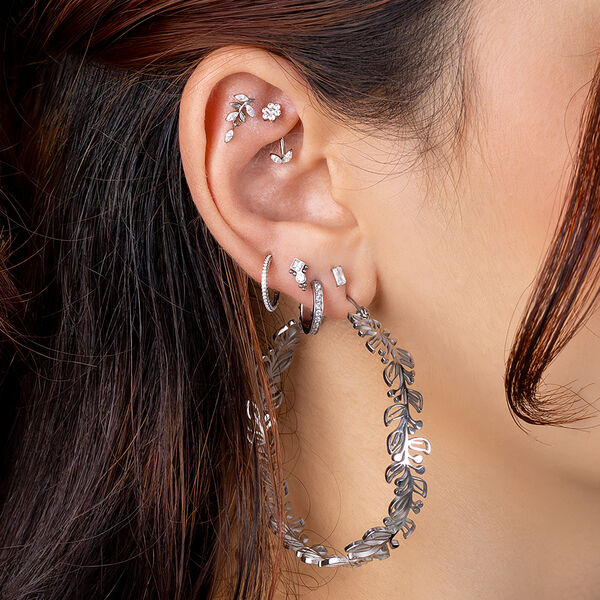 Orecchio femminile con diversi piercing a foglia d'argento e un grande orecchino pendente a foglia
