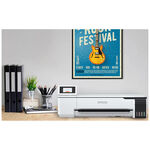 Stampante bianca Epson SureColor SC-T3100x di grande formato su una scrivania con materiali d'ufficio e piante, poster sullo sfondo