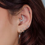 Primo piano di un orecchio con diversi accessori piercing argento e gioielli.