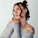 Donna con top in blu a rete e motivo tattoo su sfondo bianco