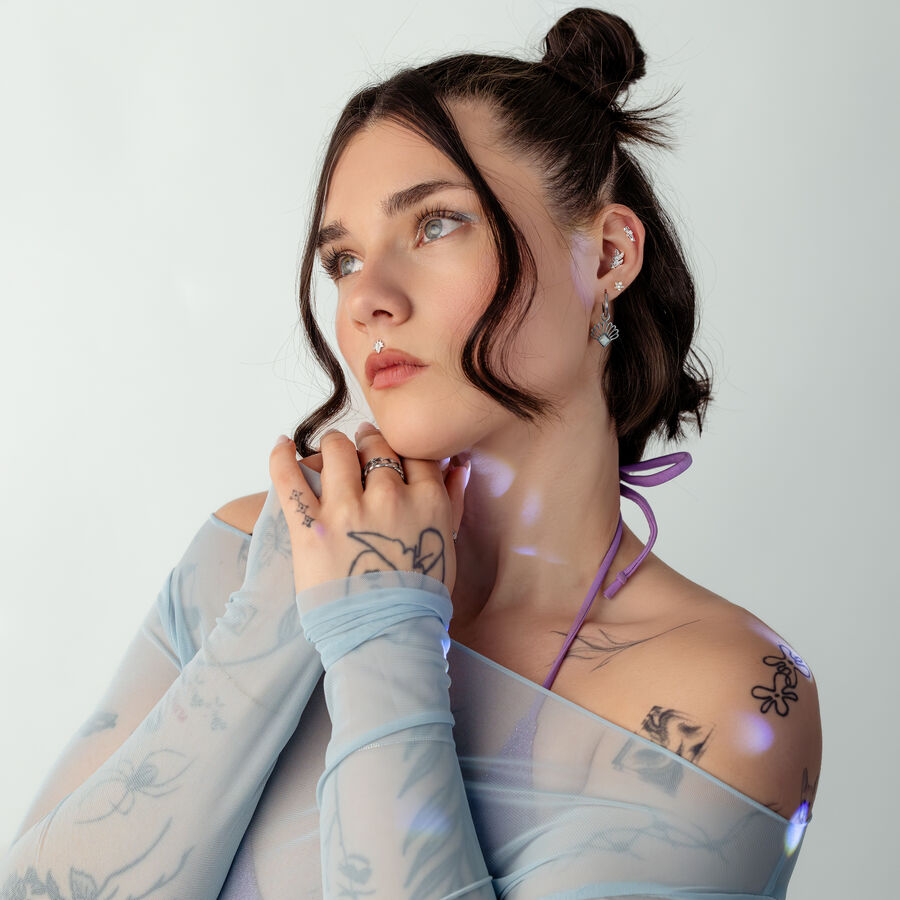 Donna con top in blu a rete e motivo tattoo su sfondo bianco
