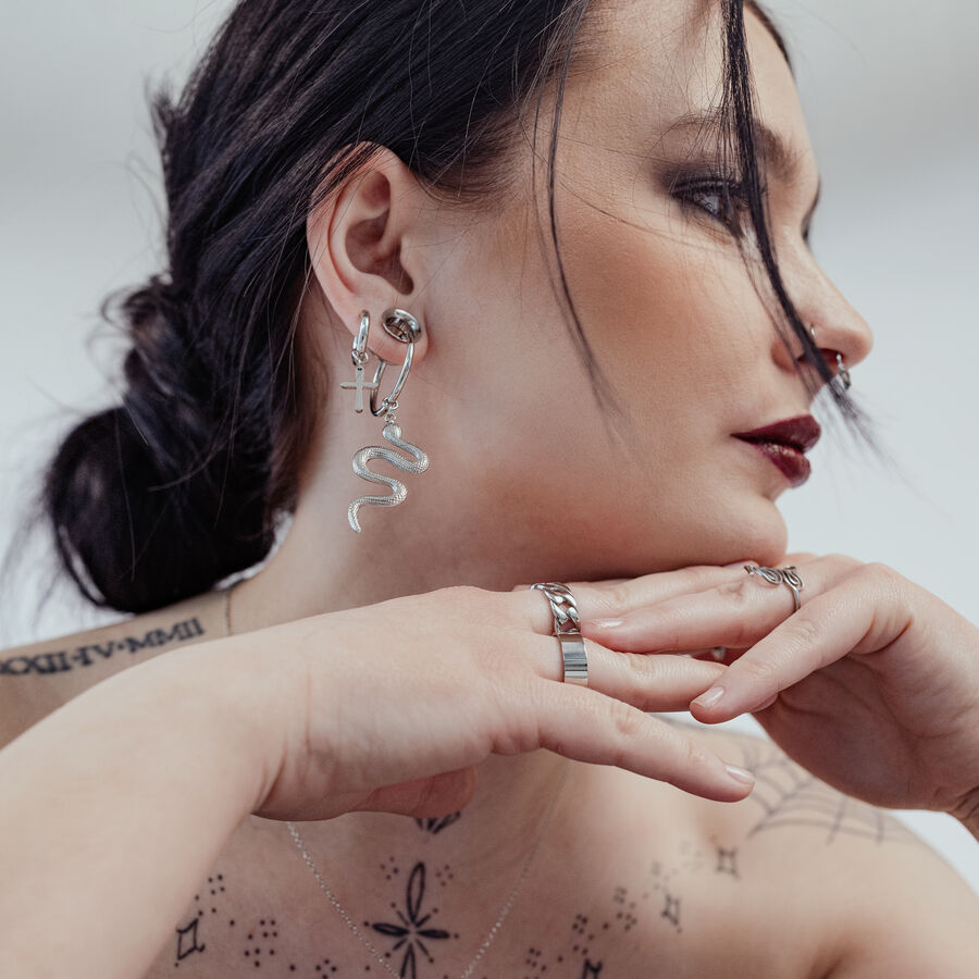 Mujer con aros Little Cross plateados y pendiente de serpiente, fondo blanco