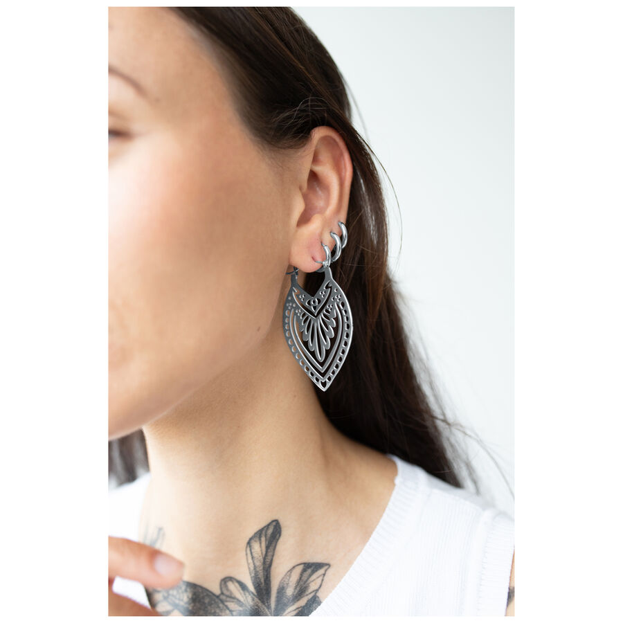 Mujer con pendientes Creek Hoops en plata, llevados en la oreja, fondo blanco