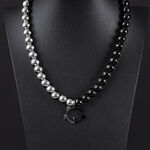 Collana in argento e nero con ciondolo a forma di gatto su sfondo nero