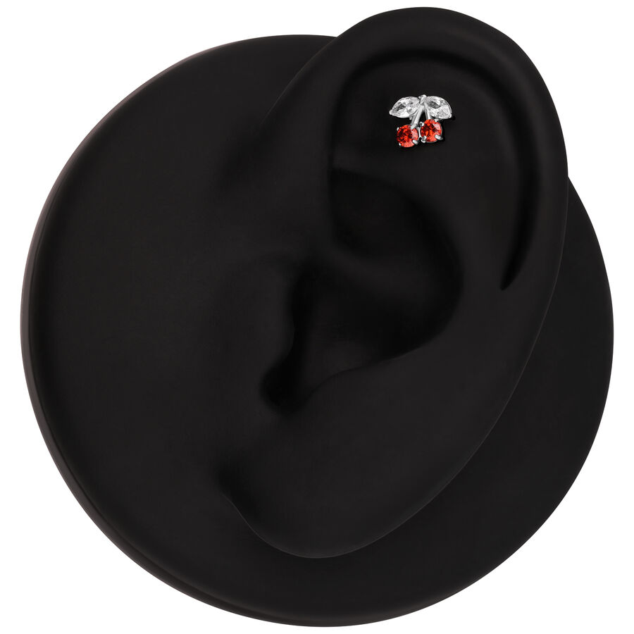 Modelo de oreja negra con accesorio de piercing plateado en forma de cereza y piedras rojas