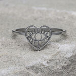 Silberner herzförmiger Ring mit Auge-Motiv auf grauem Stein