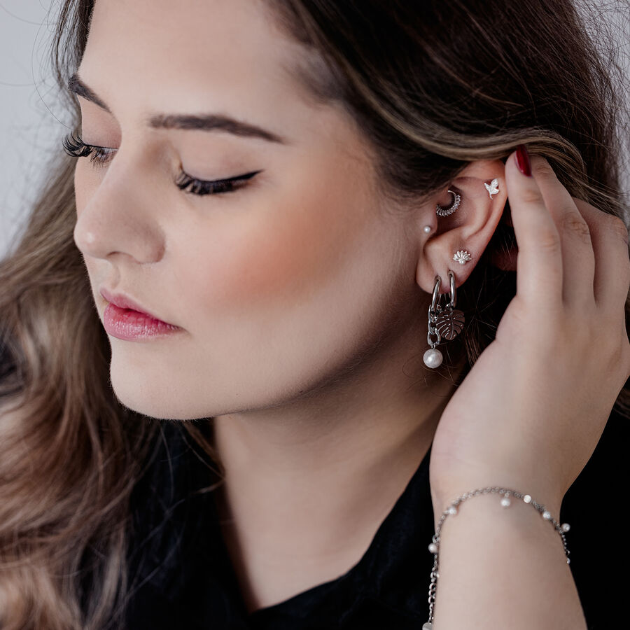 Donna con eleganti Chunky Pearl Hoops neri e argento e altri piercing all'orecchio