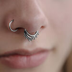 Primer plano de un Triple Oriental Clicker plateado en el septum de una cara