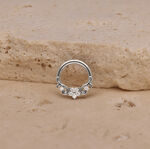 Silberner Piercing-Ring mit Blumenmotiv auf sandfarbenem Stein