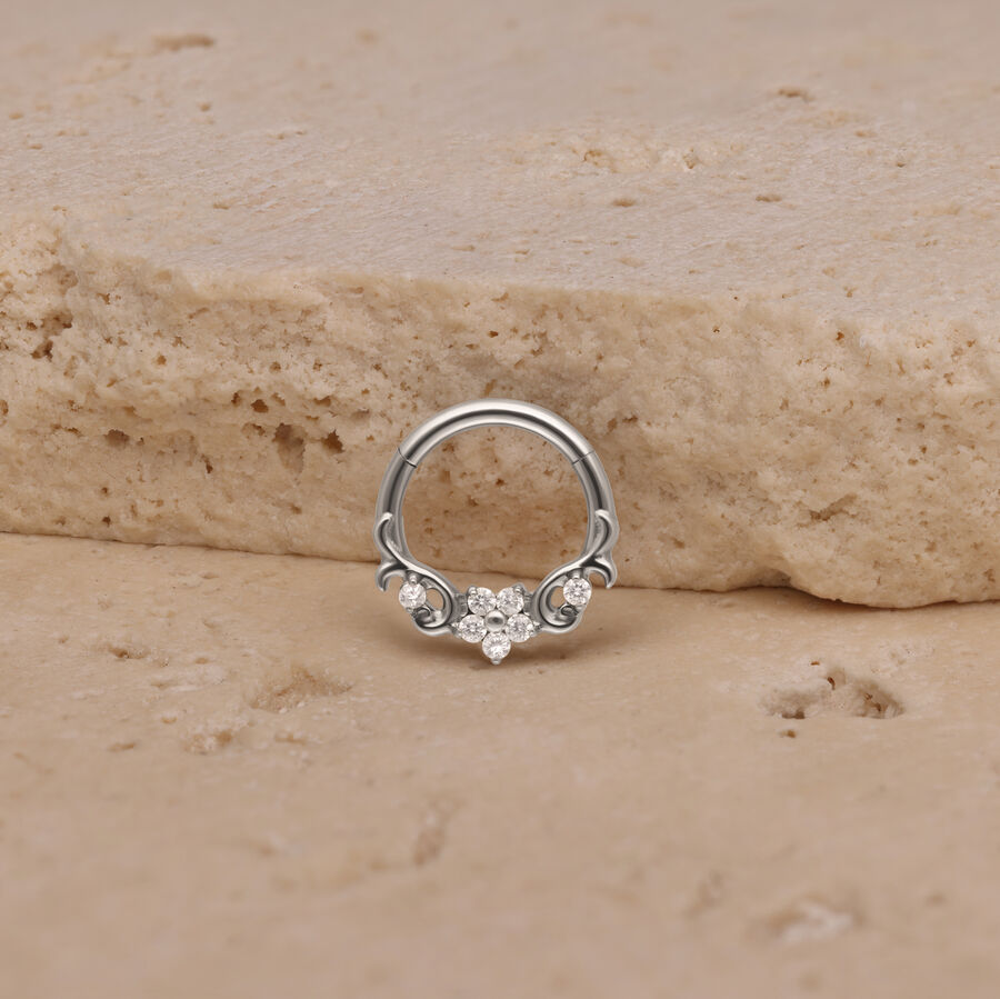 Silberner Piercing-Ring mit Blumenmotiv auf sandfarbenem Stein