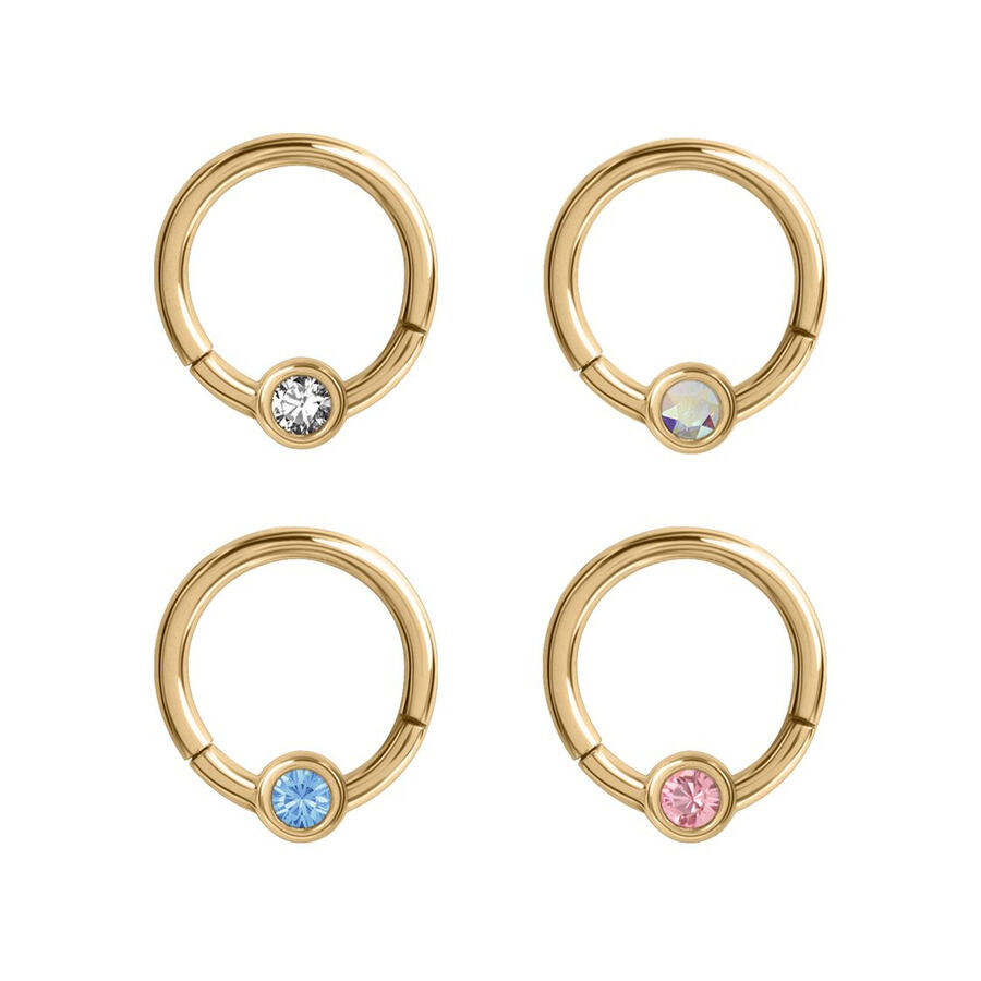 Quattro anelli piercing dorati con cristalli chiari, blu, rosa e scintillanti su sfondo bianco