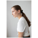 Mujer con cabello largo y liso lleva pendientes de pinchos de acero quirúrgico negro y plateado, camiseta blanca.