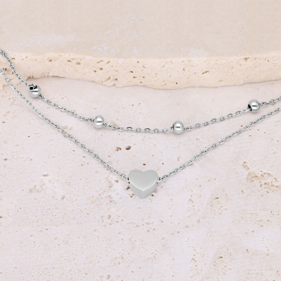 Bracciale argento a doppio filo con cuore e perline su sfondo chiaro