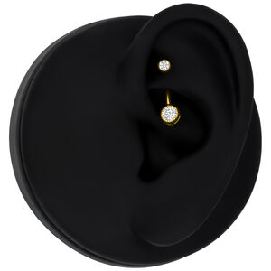 Goldenes Piercing mit klarem Kristall an schwarzem Ohrmodell