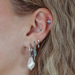 Oreja con varios piercings, incluyendo un ajuste push de plata con cristal turquesa
