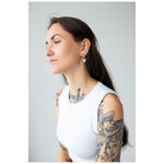 Mujer con brazos tatuados lleva Little Sphynx Hoops negros sobre fondo gris