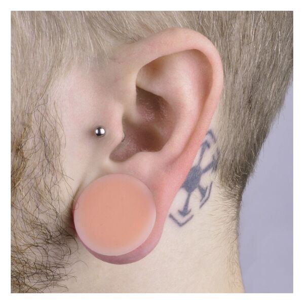 Hautfarbener Silikon Plug im Ohr getragen, Tattoo sichtbar, heller Hintergrund